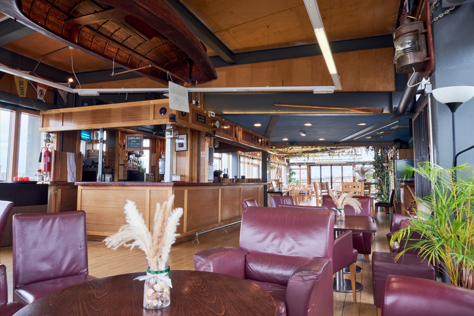 The members bar in the clubhouse with burgundy leather armchairs, wooden tables and the river through the windows