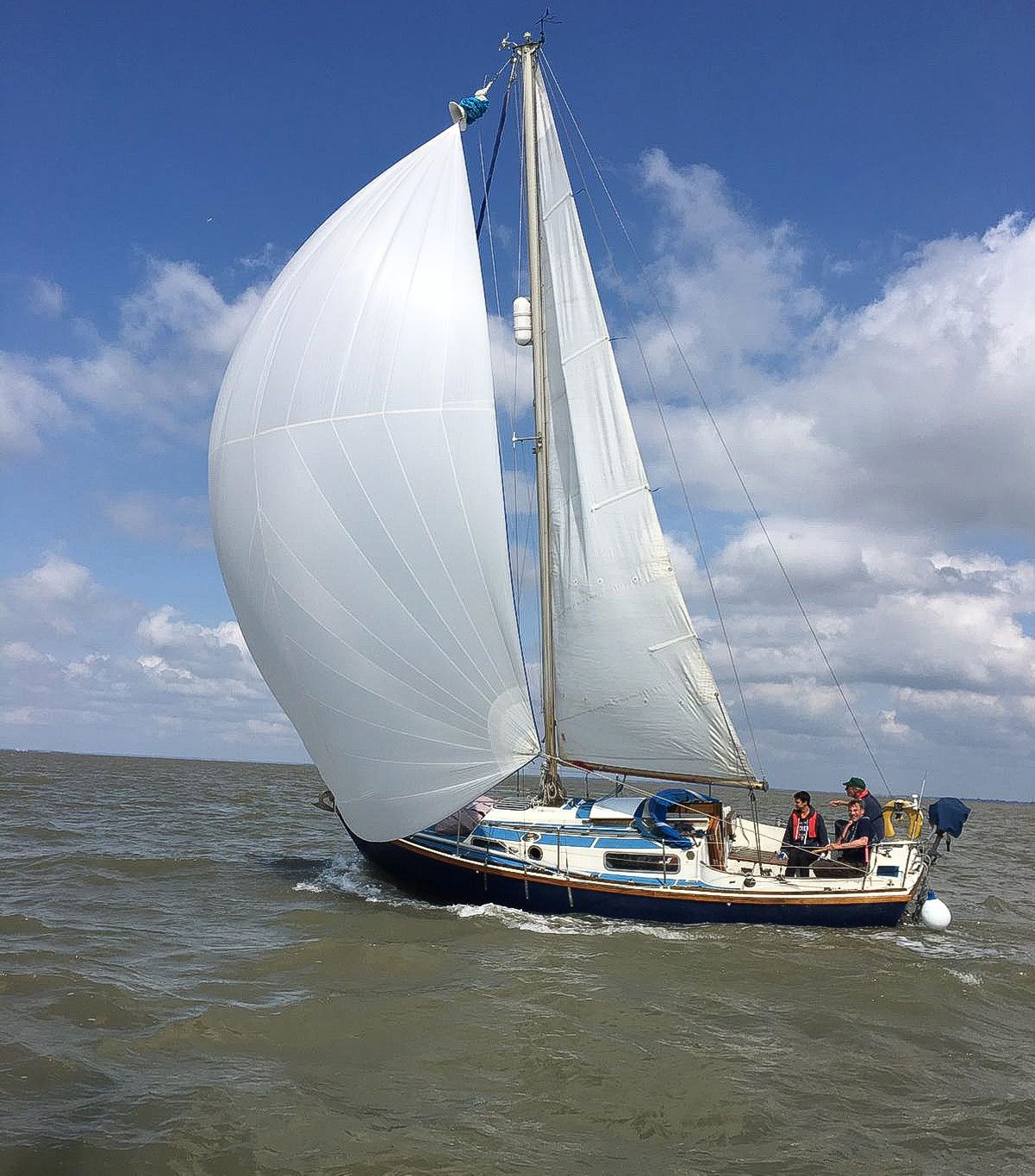 A cruiser flying a white gennaker downwind under a big sky