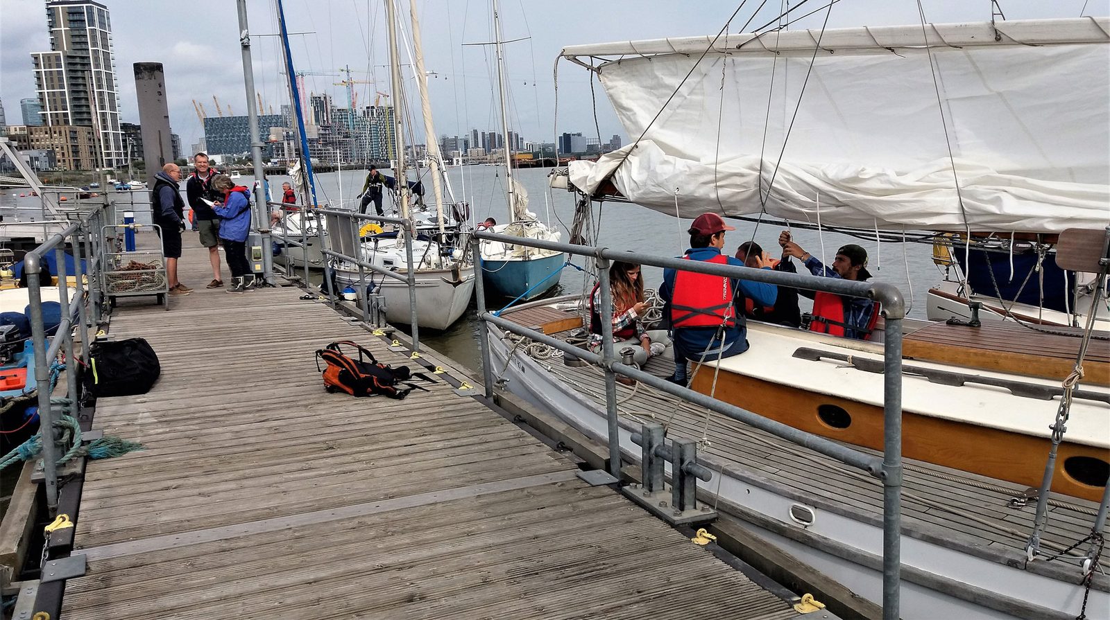Cruisers rafted up alongside the club pontoon with members on deck and the city skyline behind