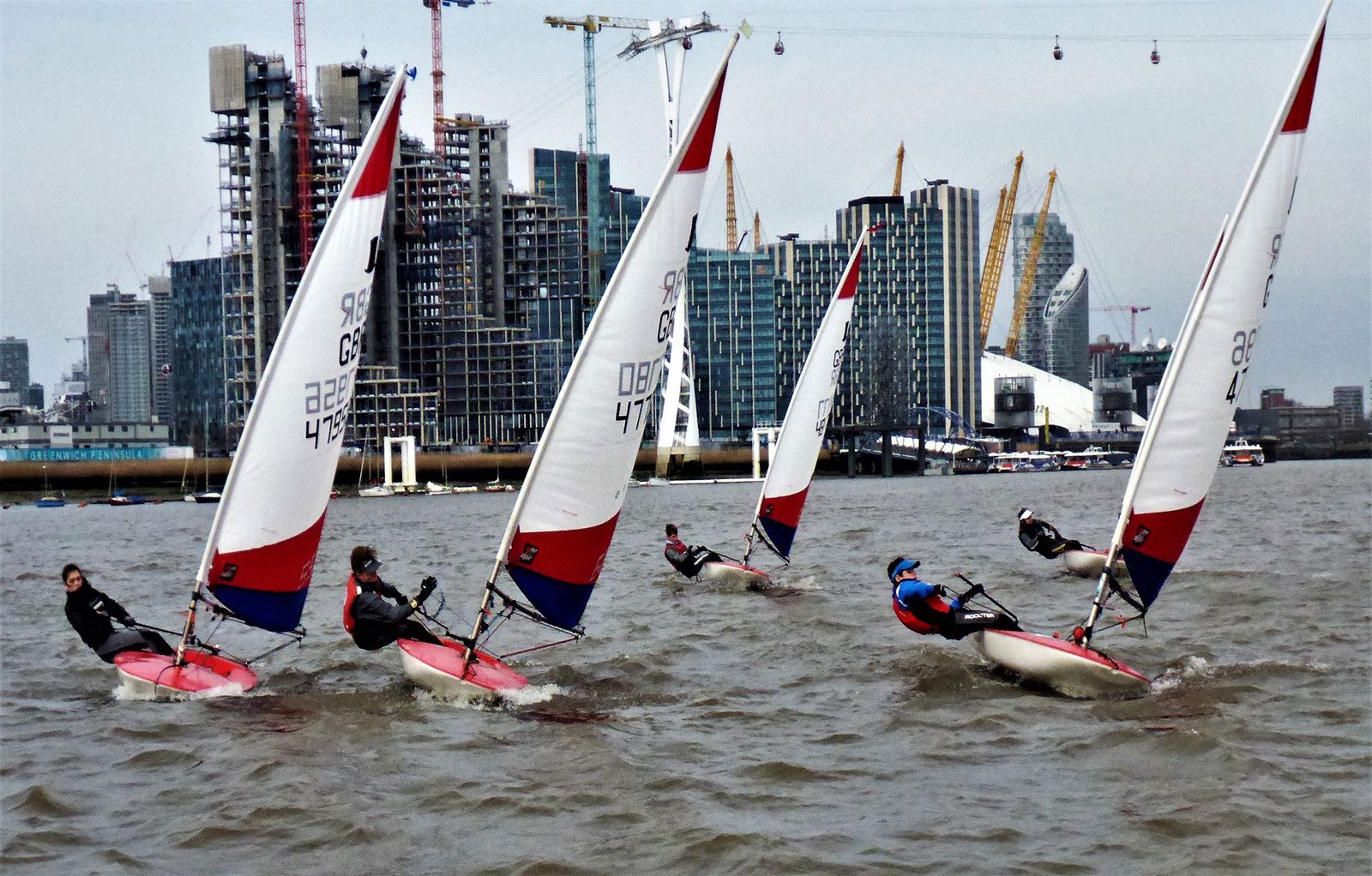 A fleet of Toppers racing on the river with the O2 and the cable car behind