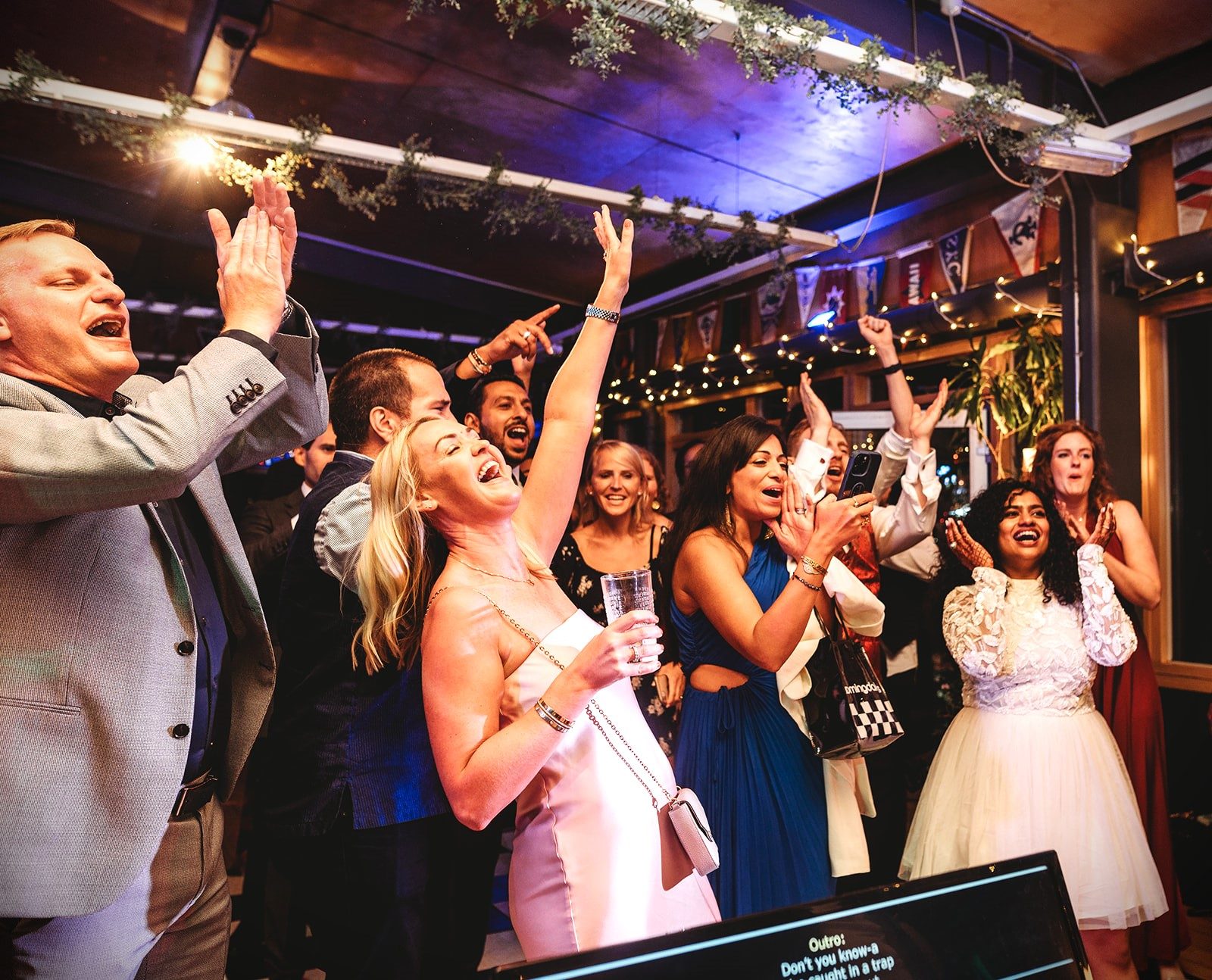 Guests with their arms in the air on the dance floor at an evening party in the River Rooms