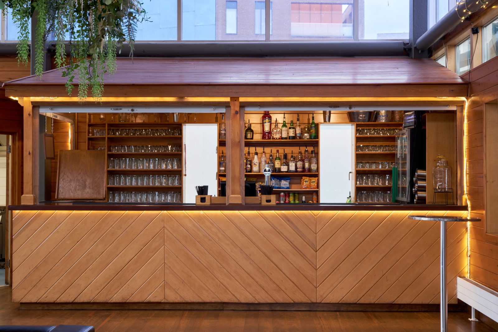 The chevron panelled wooden bar in the River Rooms with backlit shelves of spirits and glasses