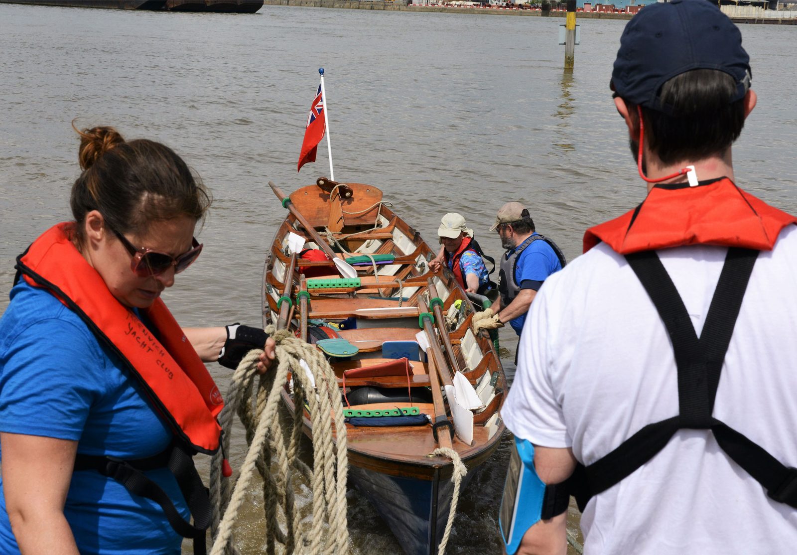 Rowers in lifejackets boarding a cutter from the pontoon