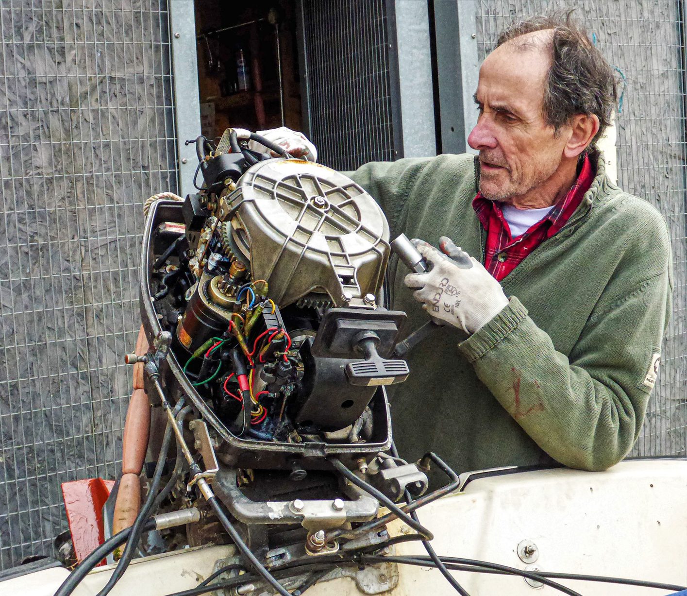 A member servicing an outboard engine in the yard